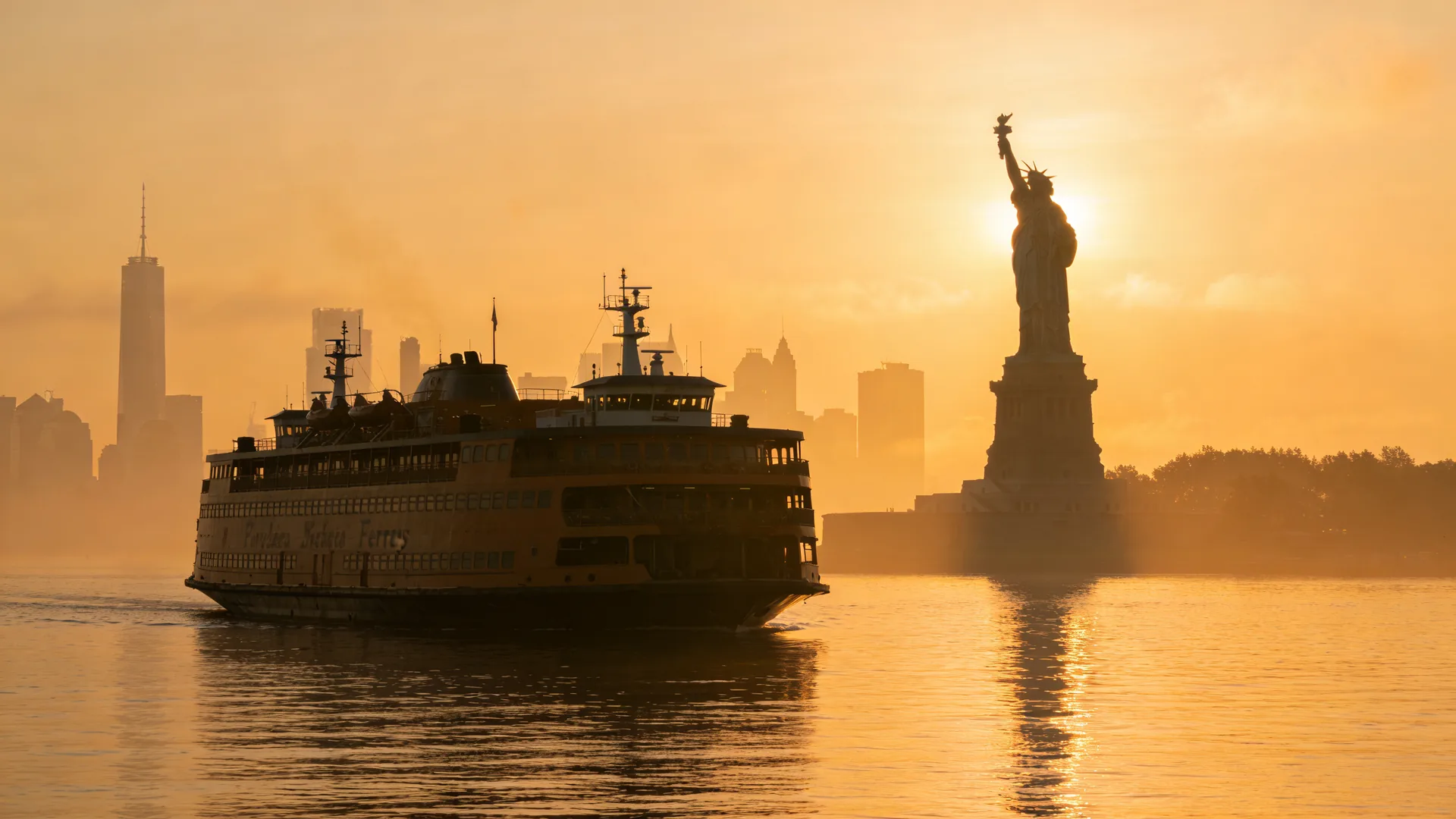 Statue of Liberty silhouetted at sunrise from a ferry — how long is a Statue of Liberty visit time planning