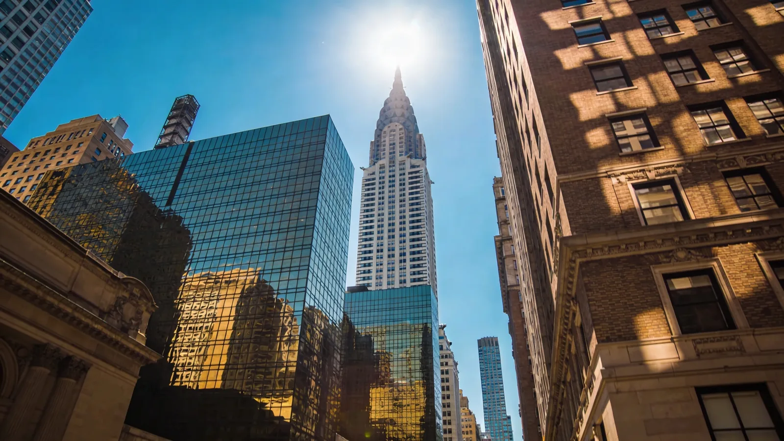 Empire State Building at noon on a clear summer day with surrounding midtown — best time to visit Empire State summer window