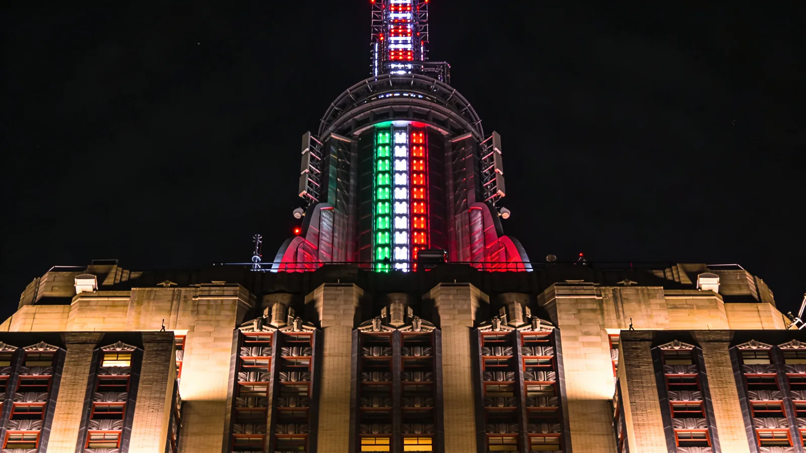Empire State Building tower crown close-up at night with LED light array showing red green and white pattern — Empire State holiday lights LED close-up