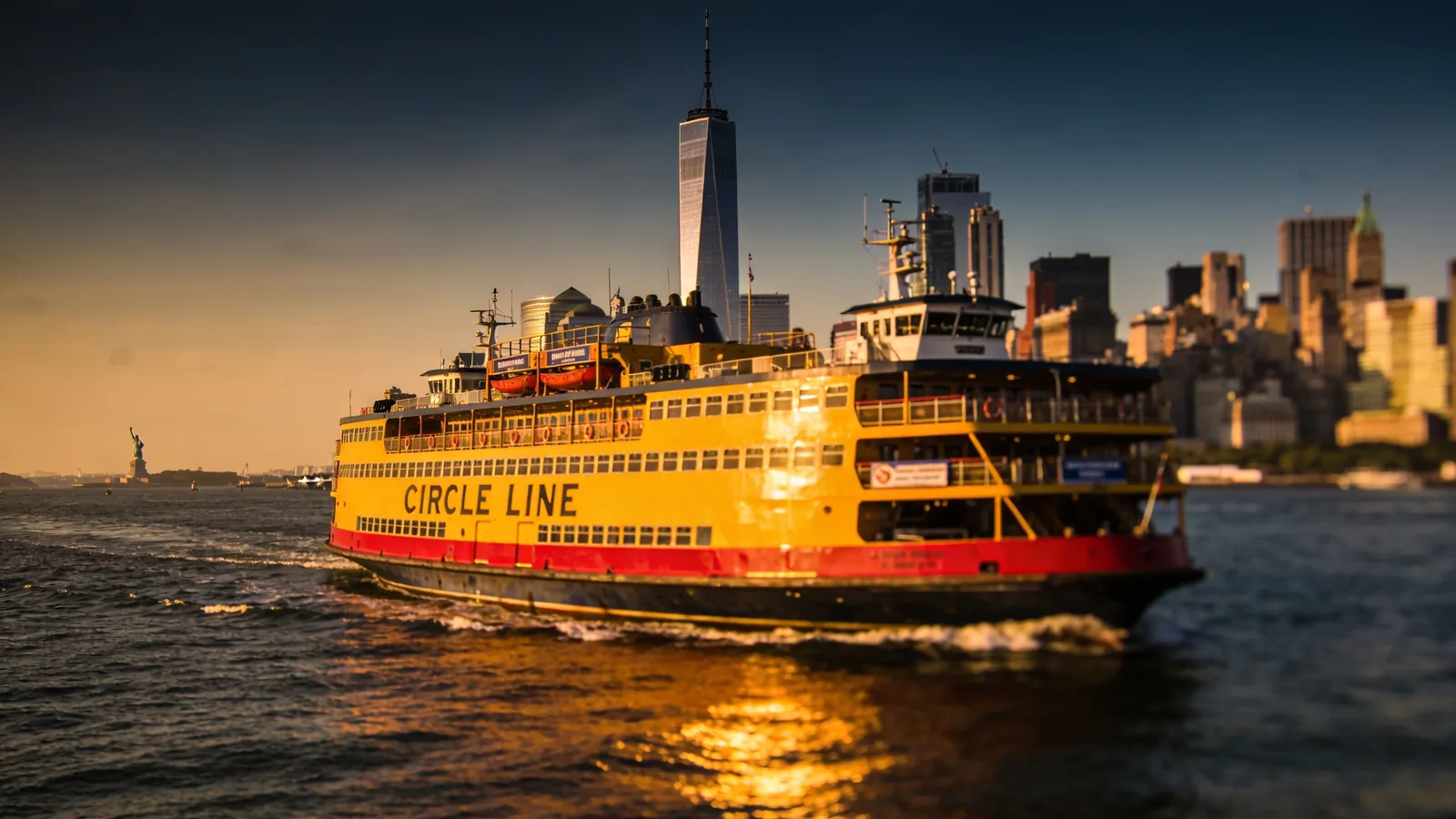 Circle Line sightseeing boat on New York Harbor with Manhattan skyline behind at golden hour — Liberty Cruise vs Circle Line harbor option