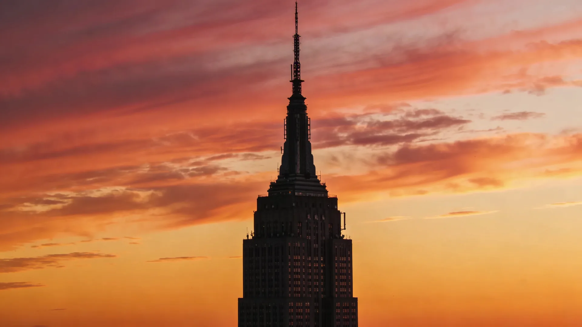 Empire State Building spire silhouetted against sunset sky — Empire State sunset tickets timing guide