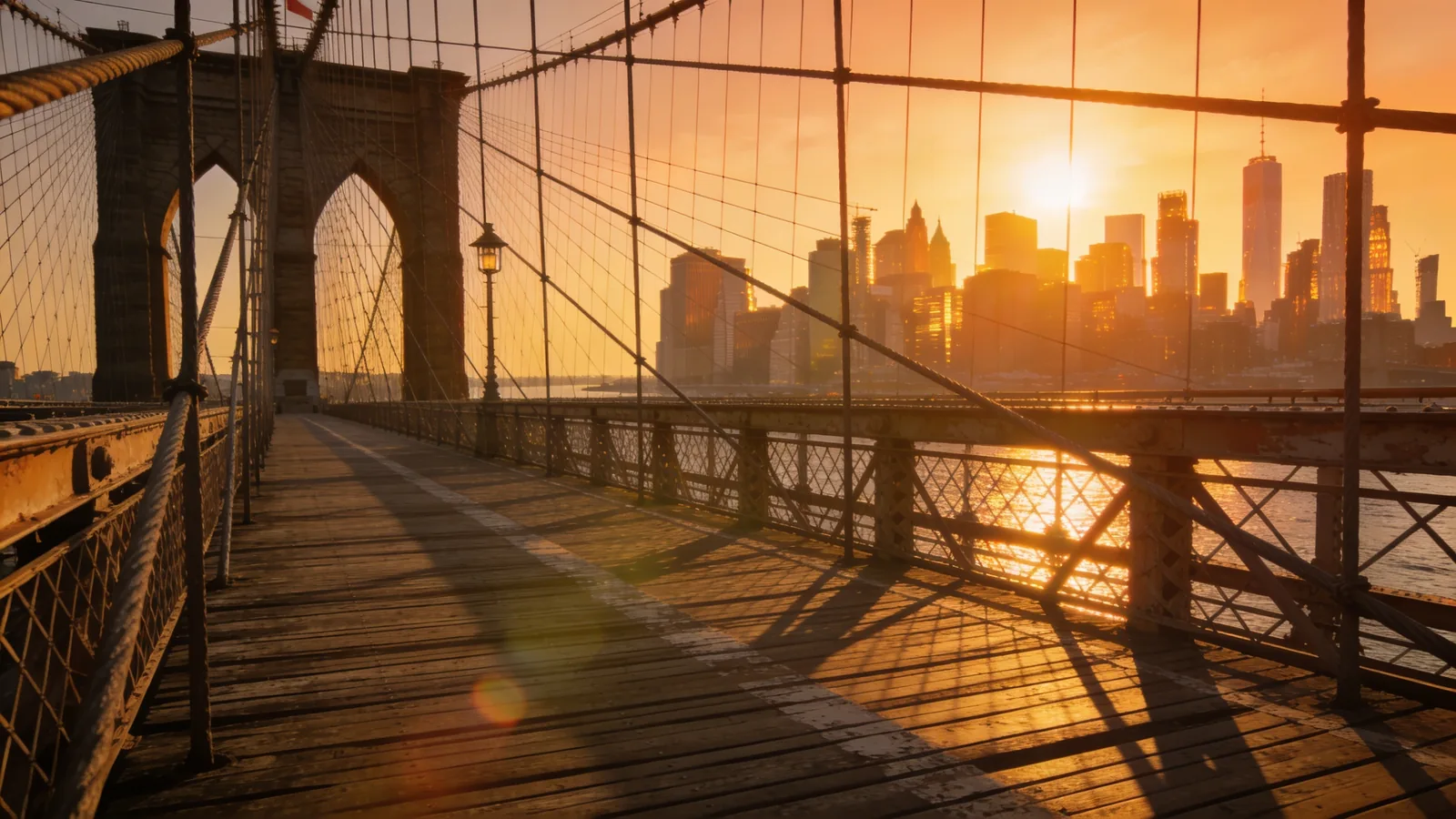 Pedestrian walkway on the Brooklyn Bridge at sunset with Manhattan skyline behind — NYC Icons tour itinerary Stop 4